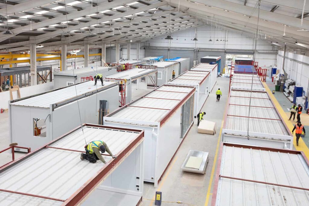 Inside view of Premier Modular's offsite construction factory. Lots of modular units being built by workers. 