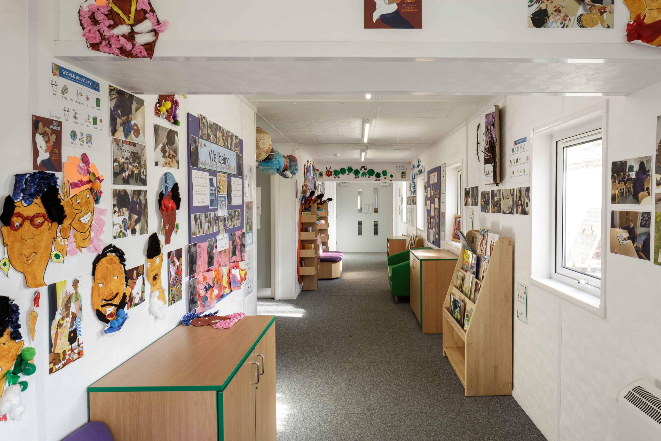 Inside modular classroom. Reading area, with childrens paintings on the walls.