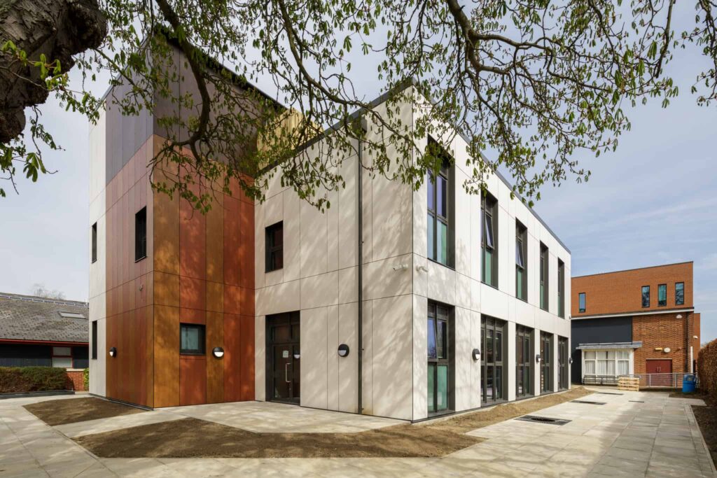 Outside a modular building. White panels, windows, alongside an extended wall with brown/orange panel.
